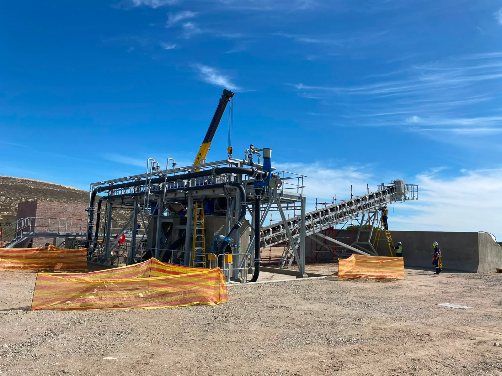 Steel processing installation with pipework, conveyor, access platforms and a crane on a MOSS project site.