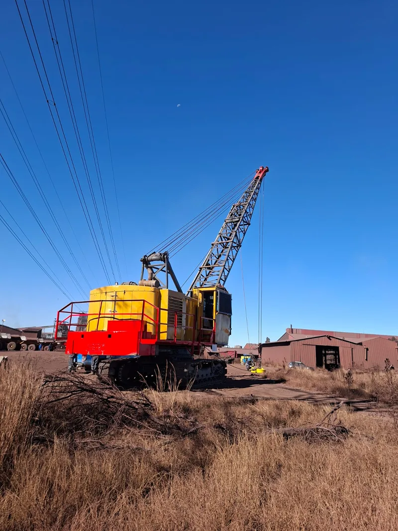 Assembled yellow and red Bucyrus tracked crane with its lattice boom raised.